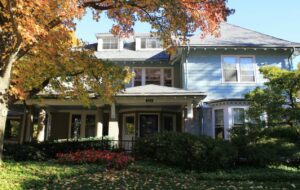 A photo of a light blue victorian house in Fall in New England