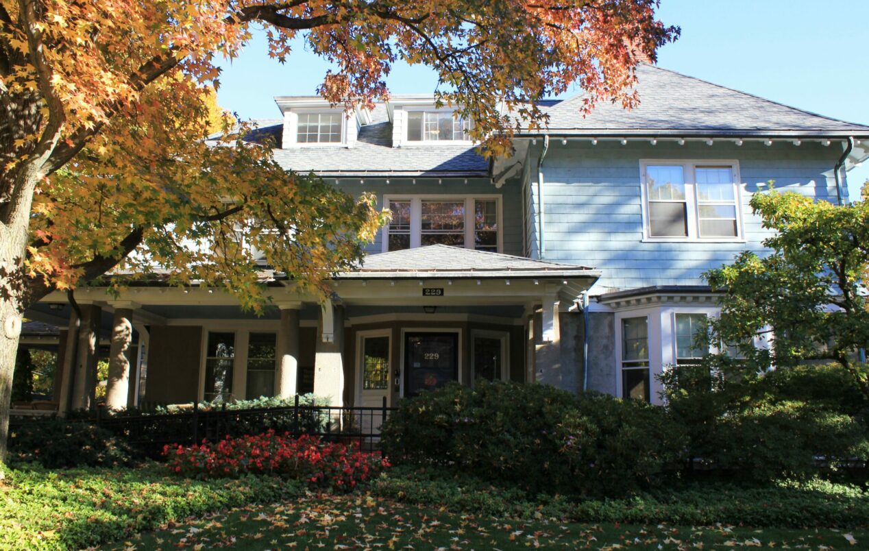 A New England fall picture of a light blue victorian house