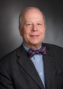 Head shot photo of a balding man in suit and bowtie